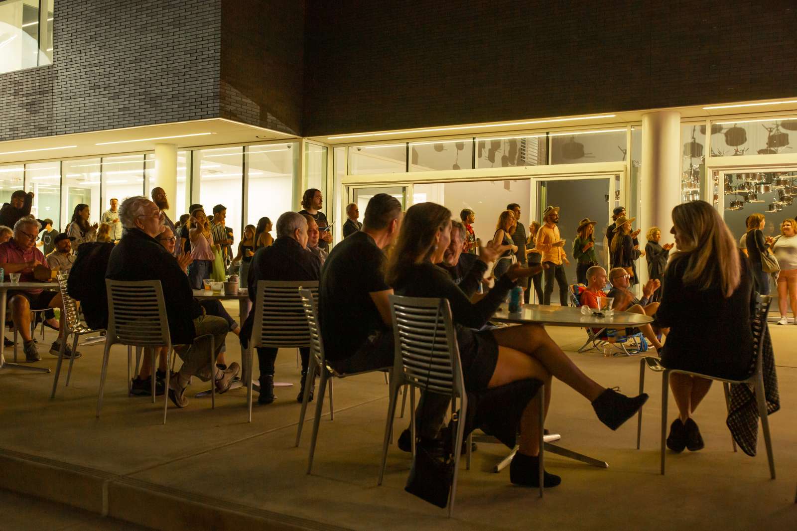 Crowd sitting in he foreground and standing in the background in low lighting